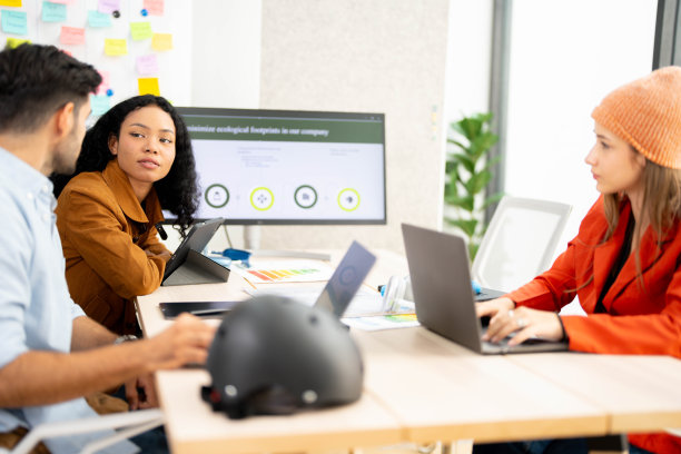 一位职业女性在办公室协作会议上讨论可持续性KPI仪表板上的数据。年轻的商业分析师在生态战略的屏幕上评估环境绩效指标。图片下载
