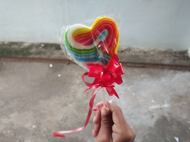 手里拿着五颜六色的心形棒棒糖图片下载