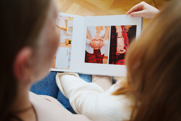 母女俩翻看一本有爸爸和怀孕妈妈照片的书。图片下载