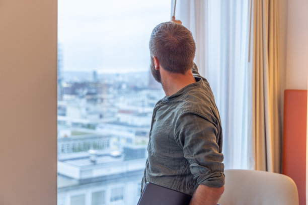一名男子从他的办公室窗户向外眺望美景的后视图图片下载