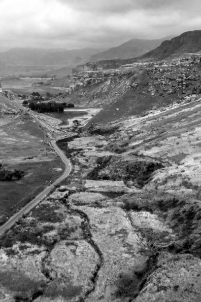 南非德拉肯斯堡山脉山谷中高速公路的黑白照片，拍摄于多云的雨天。图片下载