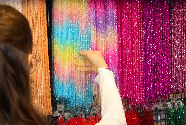 一个年轻的黑发女孩在服装珠宝店挑选红色玻璃珍珠项链时的手图片下载