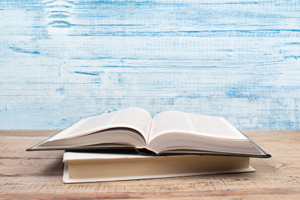 构图与精装书，扇页在木制甲板桌和蓝色背景。书堆积。回到学校。副本的空间。教育背景。图片下载