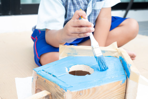 特写到孩子的手与油漆刷和蓝色。儿童绘画项目。图片下载