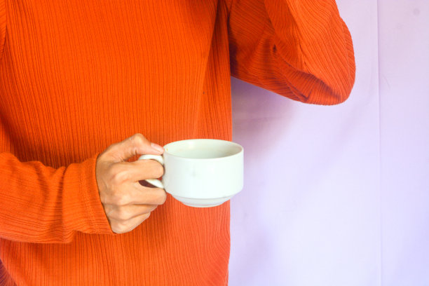 一个穿着橙色t恤的女人的画像，她喝着一杯黑咖啡，读着一本书，做着早晨的活动图片下载