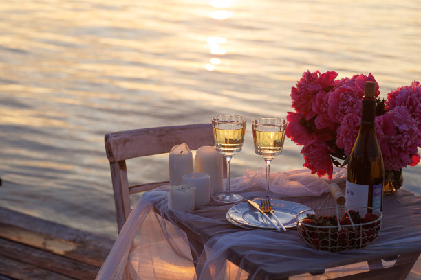 海滩上浪漫的日落晚餐。餐桌蜜月二人组与豪华的食物，一杯香槟饮料在餐厅与海景。夏日恋爱，浪漫约会就在度假概念上。图片下载