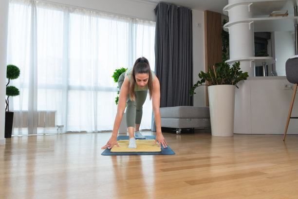 体育商务女性穿着运动服在家里的客厅里做健身瑜伽伸展运动。运动休闲理念，健康生活，平衡工作前。图片下载
