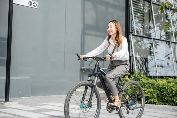 年轻的女商人戴着头盔骑着自行车去办公室上班图片下载