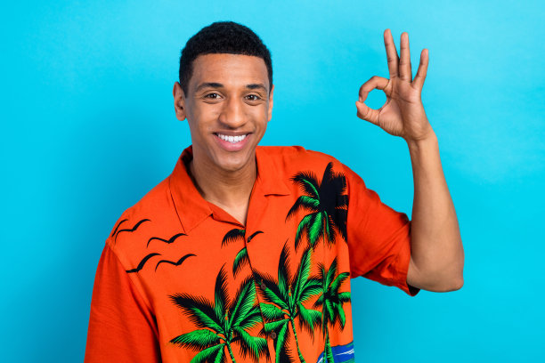 照片正面的酷家伙穿着印花衬衫显示ok标志孤立的蓝色背景图片下载