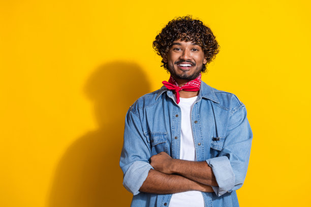 照片肖像漂亮的年轻男性双手交叉专业穿着时尚的牛仔服装红色围巾孤立的黄色背景图片下载