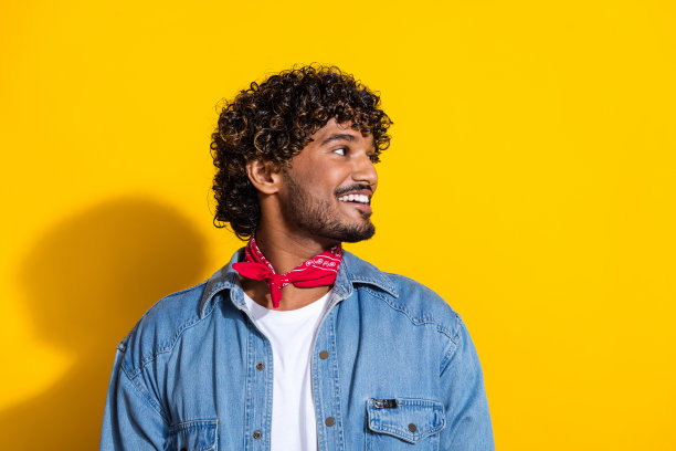 照片上的年轻人的肖像看起来侧面空的空间穿着时尚的牛仔裤服装红色围巾孤立在黄色的背景图片下载