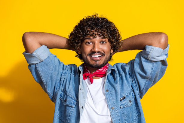 照片肖像漂亮的年轻男性双手在头昏昏欲睡穿着时尚的牛仔服装红色围巾孤立的黄色背景图片下载