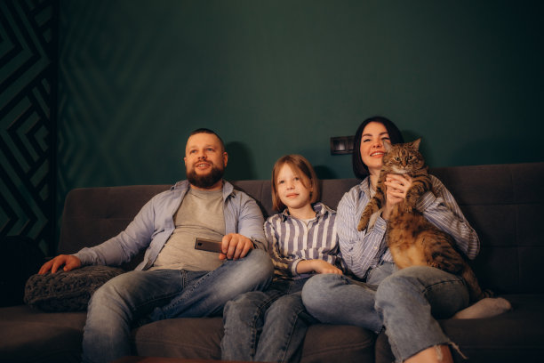 一家人坐在开放式休息室的沙发上看电视图片下载