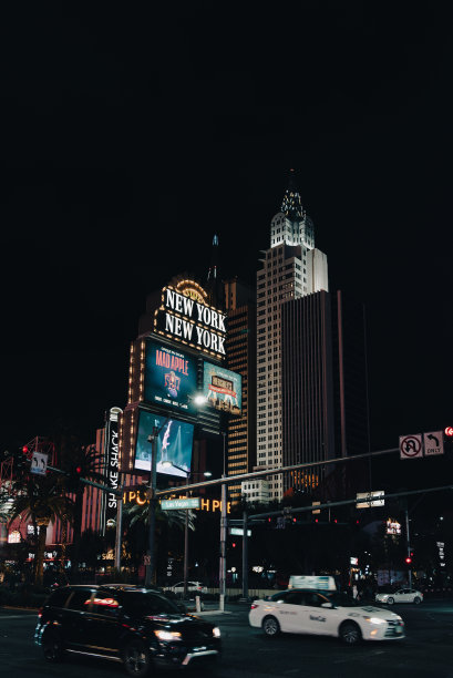 拉斯维加斯纽约区的黑暗街道。图片描绘了赌场建筑、彩旗和汽车。图片下载