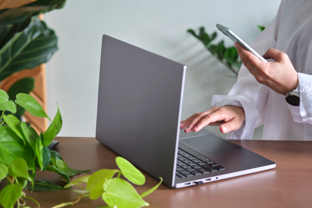 在绿色的背景下，女人的手在笔记本电脑前。图片下载