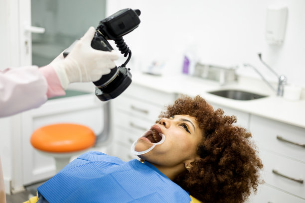 一个皮肤黝黑的女人去看牙医。一位无法辨认的牙医正在给一位阿拉伯女性的嘴拍照片。牙科摄影概念。图片下载