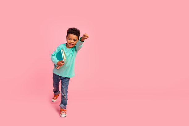 可爱小男孩的全身照片举起拳头飞学习课穿着时髦的海蓝宝石衣服孤立在粉红色的背景图片下载