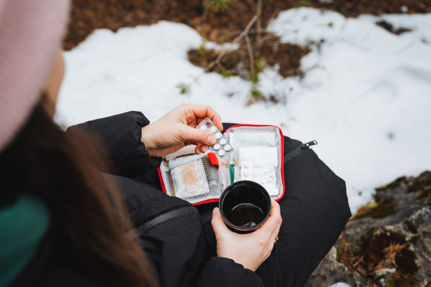 徒步旅行时的急救箱，旅行时的急救箱，止痛药，手里拿着一杯水和一片药片。图片下载