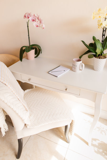 一个母亲简单的春天家庭办公空间，有粉红色和黄色的兰花，一张纸，一支笔，一部手机和一杯黑咖啡，上面写着“Mamacita”，在明亮的自然光下，白色的甲板上有奶油色的背景图片下载