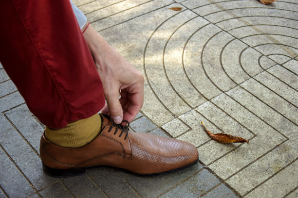 一个男人正着他的棕色经典皮鞋的鞋带。男系鞋带。特写镜头。有选择性的重点。图片下载
