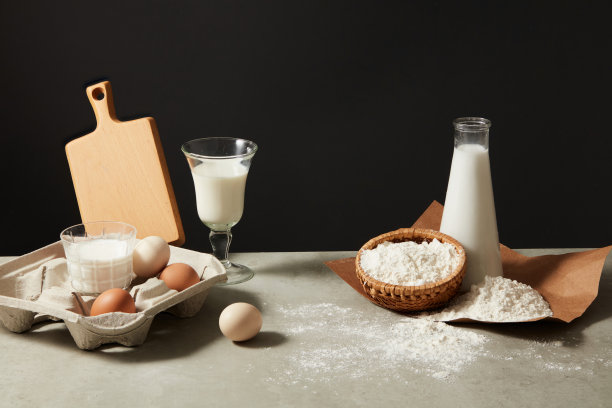 基本的黑色背景呈现了一些烘焙材料，排列在灰色的厨房桌子上，有足够的空白空间来放置文字或其他设计元素。设计照片图片下载