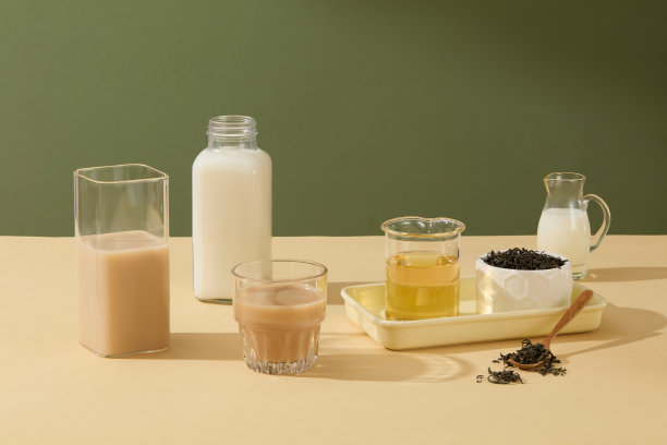 森林绿色的背景衬托着几只杯子，米黄色的桌子上放着装满饮料的杯子。用于发短信、饮料照片、美容或化妆品展示的复制空间图片下载