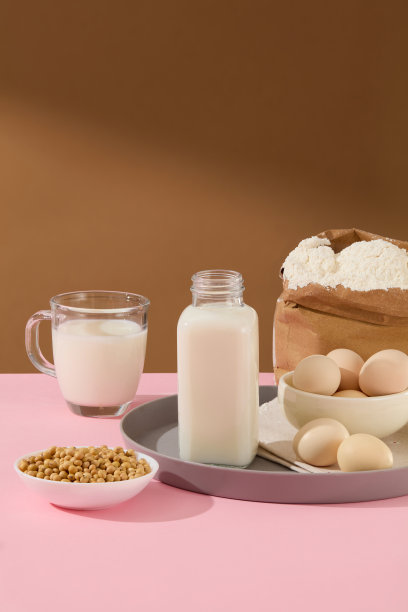 天然豆浆装在玻璃瓶和杯子里，周围是一些烘烤用的原料，纸袋面粉，一碗鸡蛋和黄豆装在白色圆碗里。它有发短信的空白空间，有烹饪概念的照片图片下载