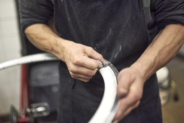 一个面目全非的人在他的车间打磨自行车轮辋图片下载