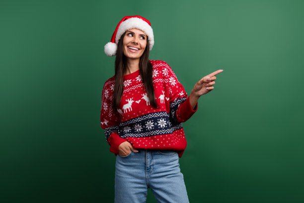 照片中甜美梦幻的女人圣诞精灵穿着圣诞装饰套头衫，显示手指空白空间孤立的绿色背景图片下载