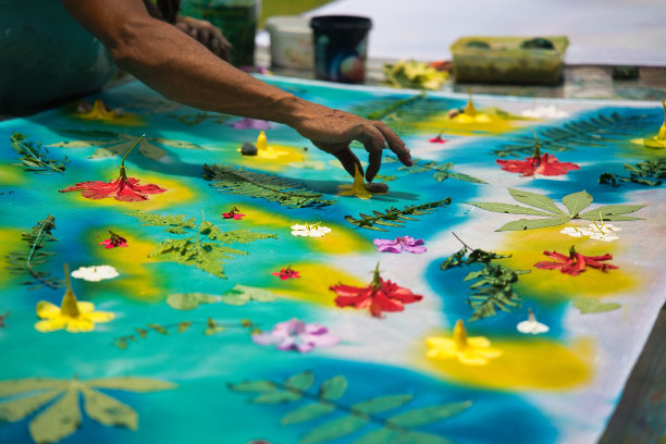 深色皮肤的男人用手在花上固定鹅卵石，用布油墨在她的帕雷奥制作车间作画，马赫塞舌尔图片下载