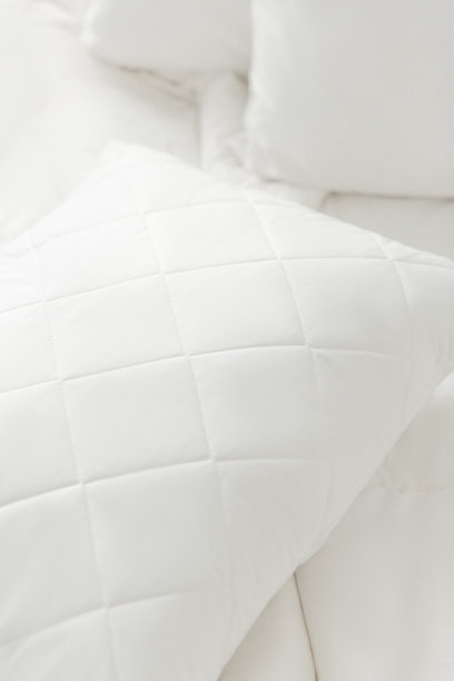 白色床上用品白色背景上的白色绗缝枕头。缓冲。家纺。特写照片，俯视图图片下载