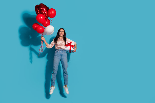 可爱的女孩穿着丝绸衬衫的全身照片拿着心气球礼盒看销售空空间孤立的蓝色背景图片下载