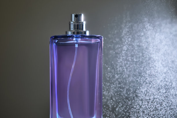紫罗兰色的瓶子里装着香水喷雾，背景是黑色的。图片下载
