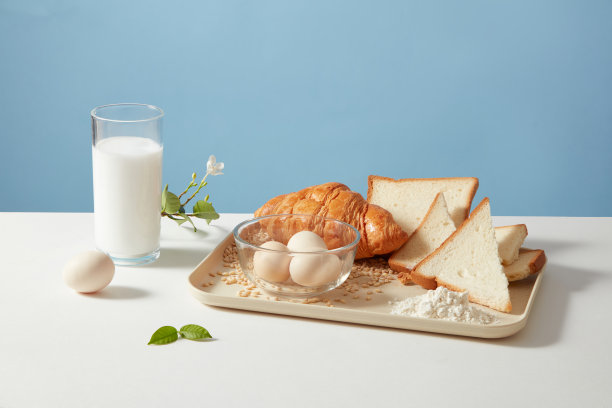 前视图照片烹饪或烘焙概念与牛角面包，三明治，鸡蛋和新鲜牛奶在蓝色背景。设计和广告的空白空间图片下载
