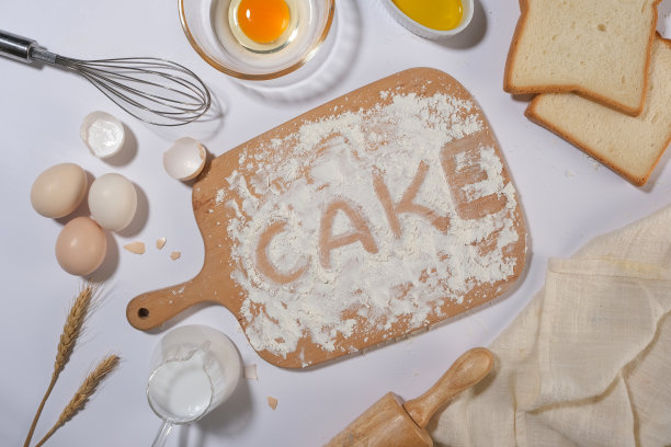 烘焙糕点或蛋糕配料的照片，白色厨房柜台上的器具，中间有一个空的木托盘。展示烹饪产品的空白空间图片下载