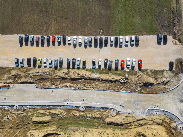 自上而下的照片——汽车停在一个砾石停车场旁边的新道路正在建设中图片下载