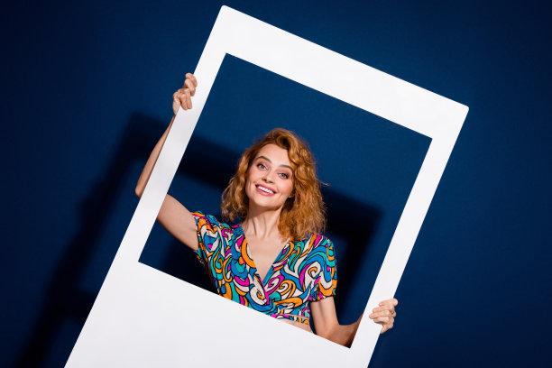 漂亮的年轻女子的照片持有相册卡穿顶孤立在深蓝色的背景图片下载
