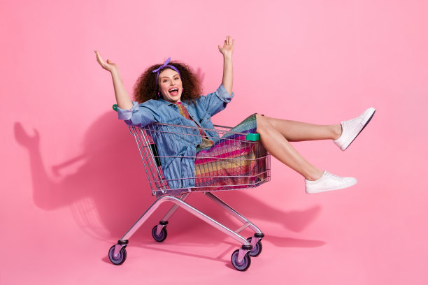 全身照片兴奋开朗的女士穿着牛仔裤装骑超市托盘空旷的空间孤立的粉红色背景图片下载