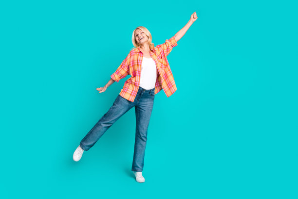 照片中开朗漂亮的女人穿着格子时尚的衣服，手拿横幅，在青色背景上空空如也图片下载