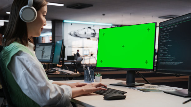 亚洲女性游戏程序员在游戏开发工作室办公室用绿屏Chromakey在台式电脑上编程。专注女性为新3D RPG电子游戏设计游戏玩法图片下载