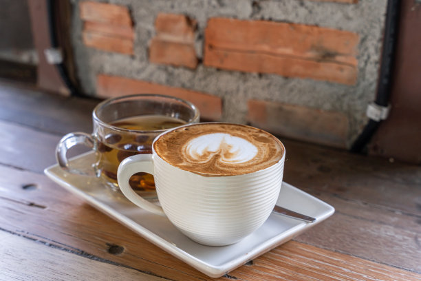 热咖啡拿铁与拉花艺术牛奶泡沫在杯子杯，热茶在木桌子上的顶部视图。作为早餐的咖啡，在复古风格的咖啡馆里，在商务期间工作概念图片下载