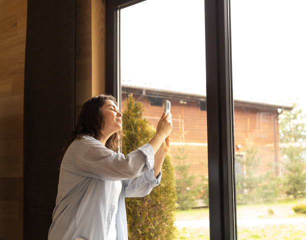 年轻女子用手机透过她家的窗户拍了一张照片图片下载