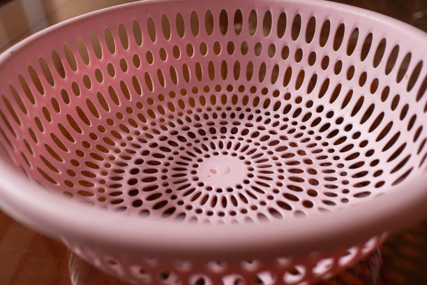 近景:木桌上的果篮呈圆形，上面有粉红色的洞图片下载