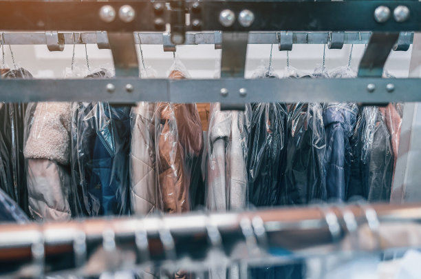 在干洗店的衣架上清洗衣服。带清洁物品衣架的输送机。图片下载