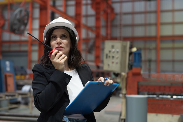 女工在工业工厂的生产线上使用通讯无线电控制工作。女检验员在工厂检查生产过程图片下载