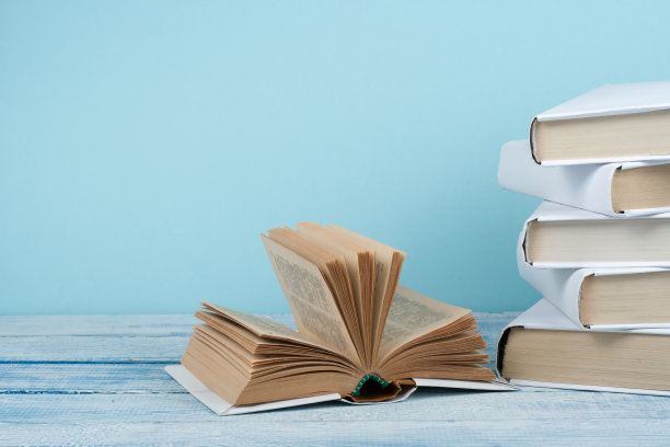 书堆积。打开书，精装书在木桌和蓝色背景。回到学校。文本的复制空间。图片下载
