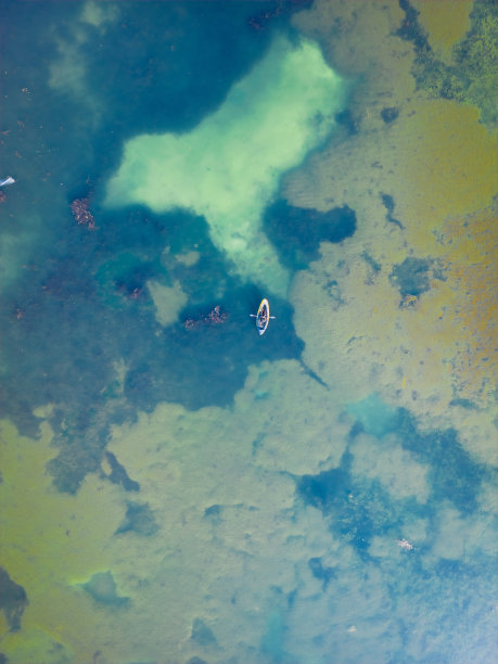 夏天，一名男子在湖上的黄色橡皮皮艇上游泳，无人机拍摄的照片。图片下载