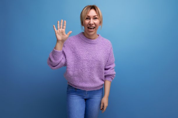 穿着紫色连帽衫的可爱金发年轻女子在蓝色背景上展示了她的手掌图片下载