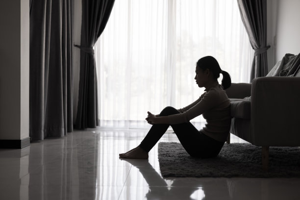 忧郁的女人，忧郁的少女的剪影独自坐在黑暗的房间里。黑白照片。图片下载