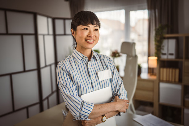 日本成熟女性在办公室拿着笔记本电脑的照片图片下载